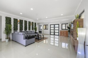 A spacious living room with a grey sofa, a coffee table, and a bookshelf.
