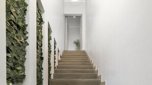 Eine Treppe mit Holzdielen und weißen Wänden, die zu einer runden Leuchte führt.