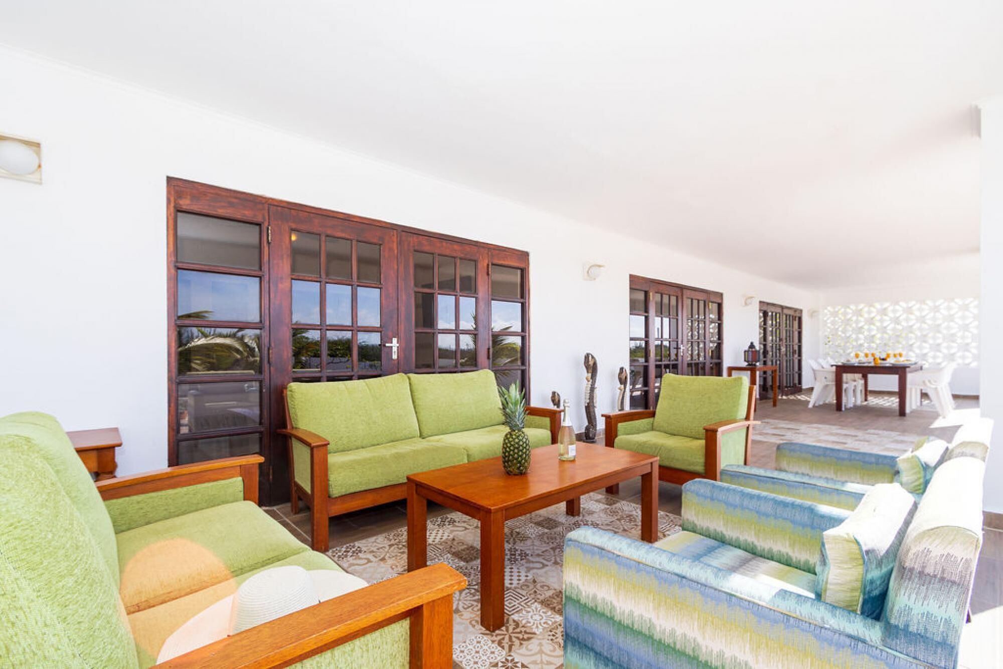 A spacious living area with a green sofa, a blue patterned sofa, and a wooden coffee table.