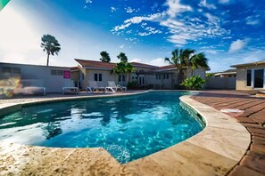 A swimming pool with lounge chairs, a tiled deck, and a clear blue sky.