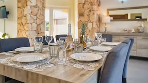 A dining table set with plates, glasses, and a bottle, surrounded by chairs. - Spacious 6BR Villa w Pool Close2beach Sleeps 16 (Noord)