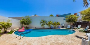 A swimming pool with a pink flamingo float, surrounded by palm trees and lounge chairs. - Sleeps 16 Palm Beach - 6BR Villa w Private Pool (Noord)