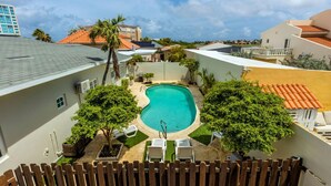 A residential area with a swimming pool surrounded by greenery and a wooden fence. - Sleeps 16 Palm Beach - 6BR Villa w Private Pool (Noord)