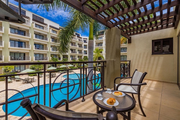 Relax on the balcony with a view of the pool, featuring a table and chairs.