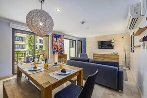 Enjoy a meal for two at the dining table, surrounded by a comfortable seating area and a large abstract painting.