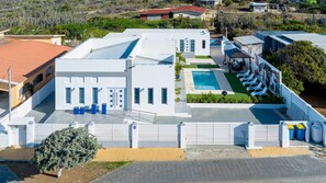 A modern house with a swimming pool, a covered patio, and a fenced yard. - Boggey s Villas - Xander Bogaerts 5BR 7BA w Pool (San Nicholas Noord)