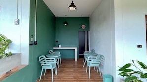 A modern interior with a wooden ceiling, green walls, and a central seating area with chairs and a table. - Norn Na Homestay Chanthaburi (Chanthaburi)