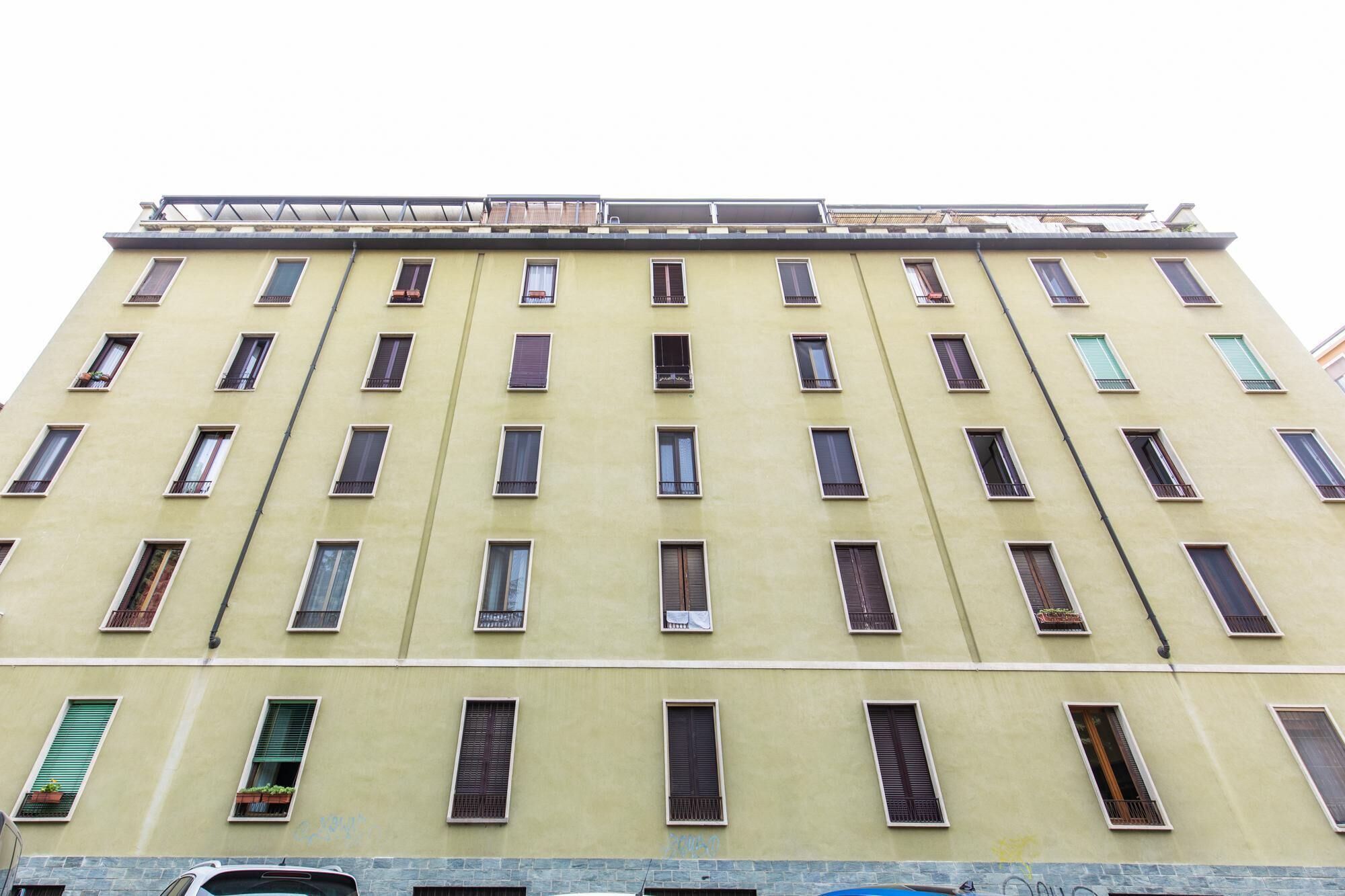 Ein mehrstöckiges Gebäude mit einheitlicher Fassade, das regelmäßig angeordnete Fenster und Balkone aufweist.