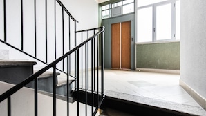 A staircase with black railings leading to a wooden door at the top. - Bellarmino 21 in Milano (Milan)