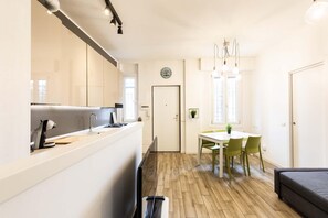 Une cuisine moderne dotée d’une cuisinière et d’un évier intégrés, un coin repas avec une table et des chaises, et un salon avec un canapé.