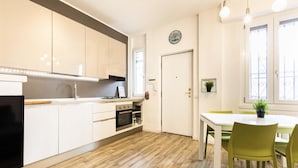 A modern kitchen with white cabinets, a stove, and a dining area with a table and chairs. - Bellarmino 21 in Milano (Milan)