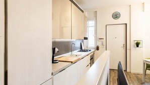 A modern kitchen with light-colored cabinets, a wooden countertop, a built-in stove, and a window providing natural light. - Bellarmino 21 in Milano (Milan)