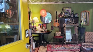 A room with a yellow door, a red and white patterned rug, a guitar, a mirror, and various decorative items. - Athensmusic Gem 1 mile from Town (Athens)