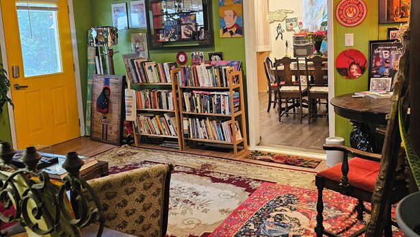 A cozy room with a bookshelf, a dining area, and a large rug. - Athensmusic Gem 1 mile from Town (Athens)