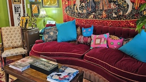 A cozy living room with a red velvet sofa, a wooden coffee table, and a tapestry on the wall. - Athensmusic Gem 1 mile from Town (Athens)