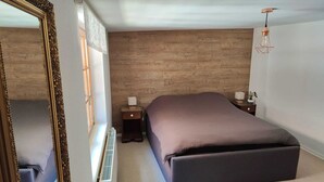 Une chambre à coucher avec un grand lit, une table de chevet avec une lampe, une commode et un miroir.