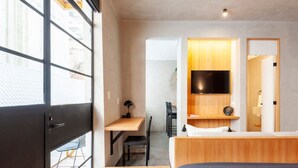 Quarto de hotel moderno com uma cama, uma escrivaninha e uma televisão.