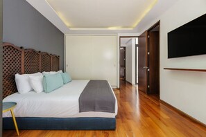Ein Hotelzimmer mit einem großen Bett, einem an der Wand montierten Fernseher und einem hölzernen Kopfteil.