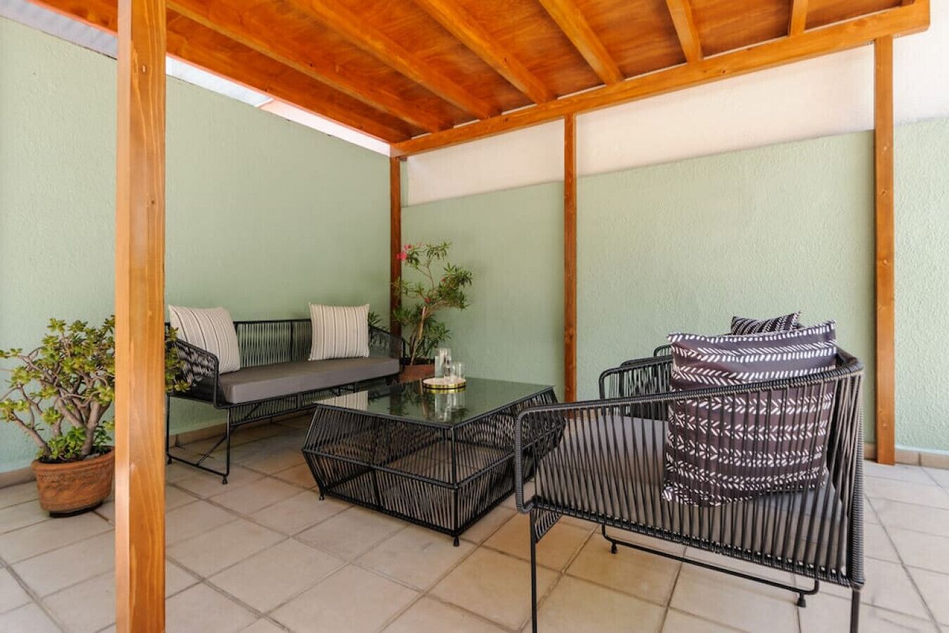 Une terrasse couverte avec une table et des chaises, un canapé et une plante en pot.