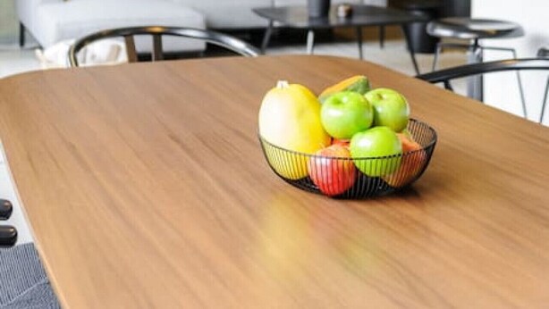 A modern living room with a wooden dining table, a bowl of fruit, a sofa, and a hanging pendant light. - Stylish 2-Bdr haven in the heart of Roma Norte (Ciudad de México)