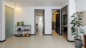 A modern hallway with a bookshelf, potted plants, and a clear view into another room. - Stylish 2-Bdr haven in the heart of Roma Norte (Ciudad de México)