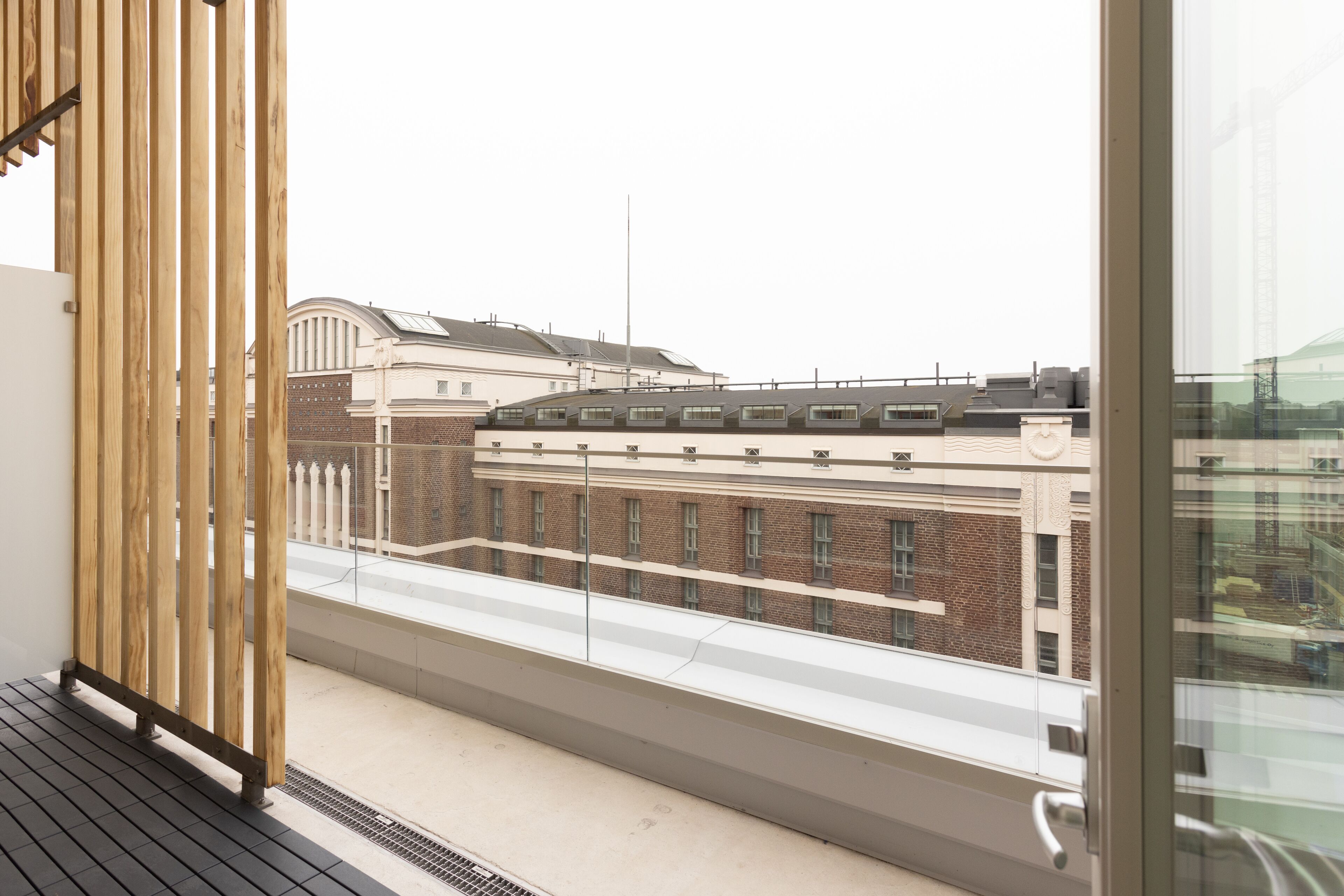 A balcony with a view of a brick building with multiple windows and a flat roof.