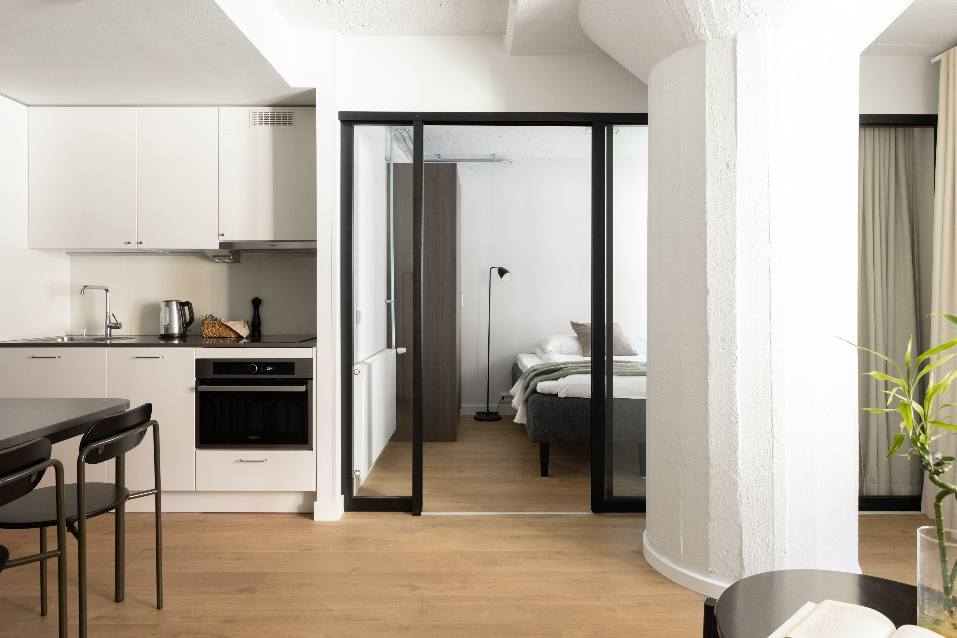 A modern apartment with a kitchen, dining area, and a bedroom.