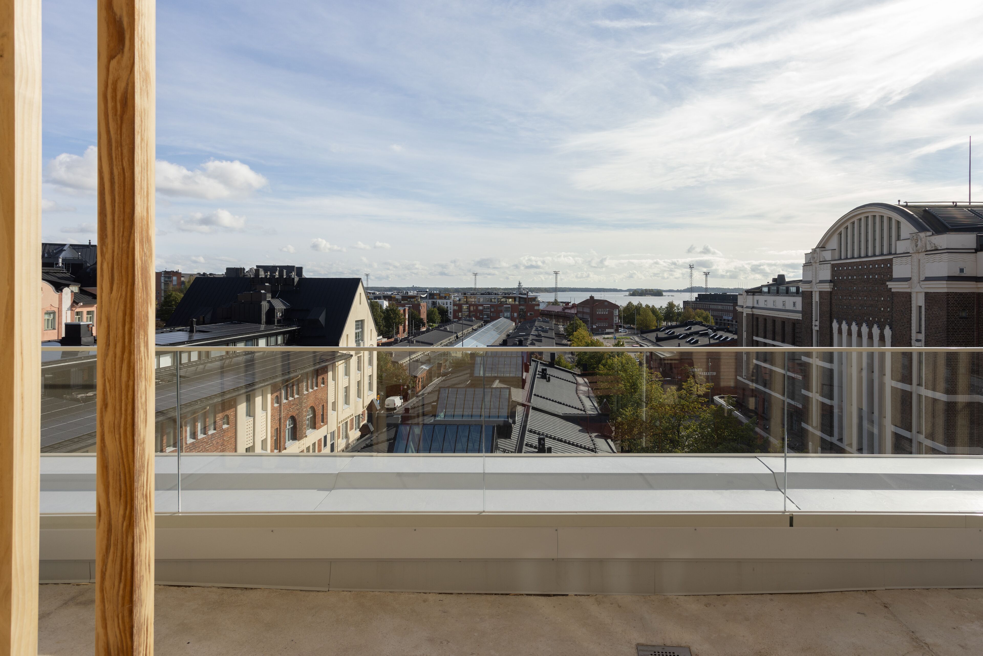 A view from a balcony overlooking a cityscape with buildings, a river, and a clear sky.