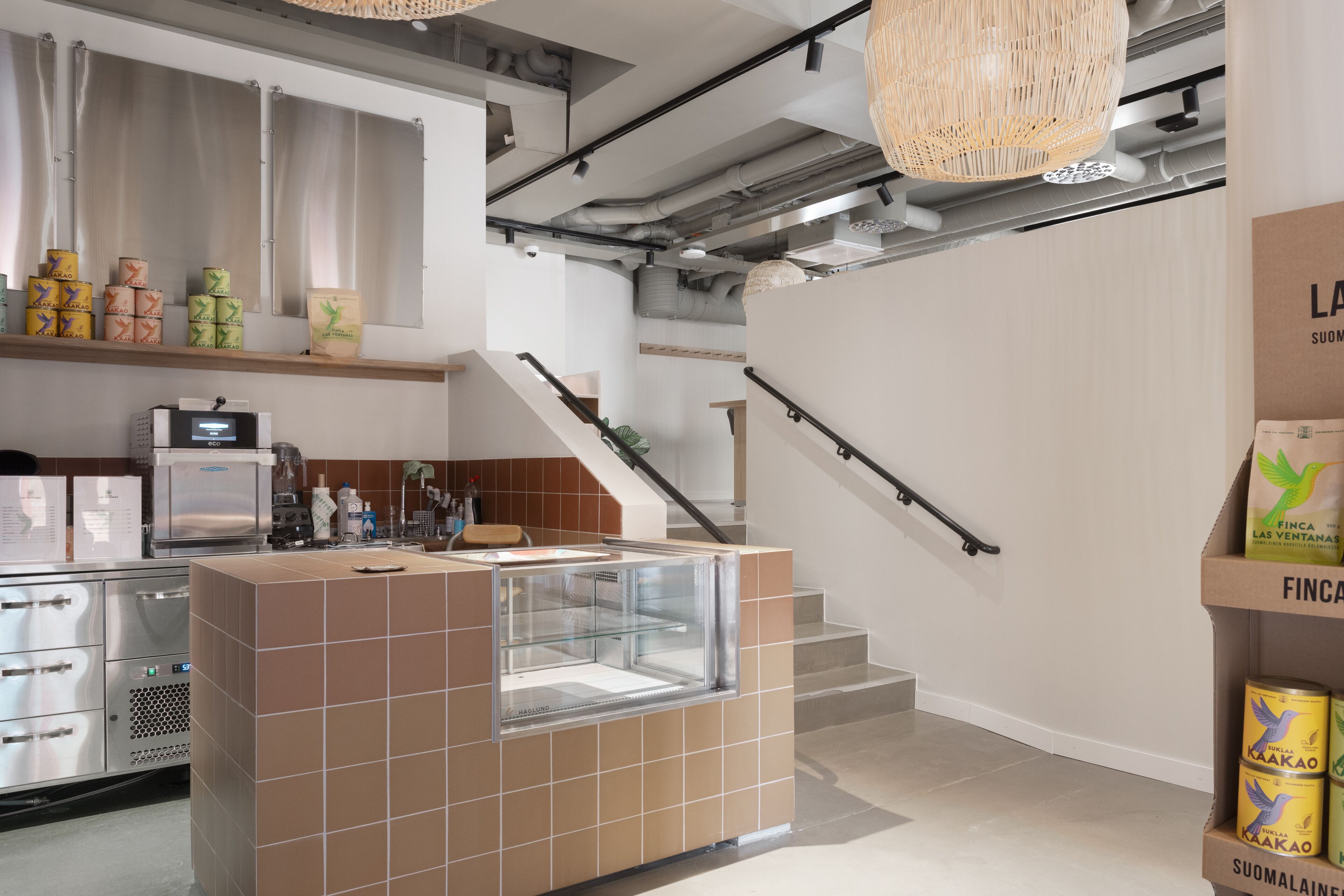 A modern kitchen with a central island, stainless steel appliances, and a staircase with a handrail.