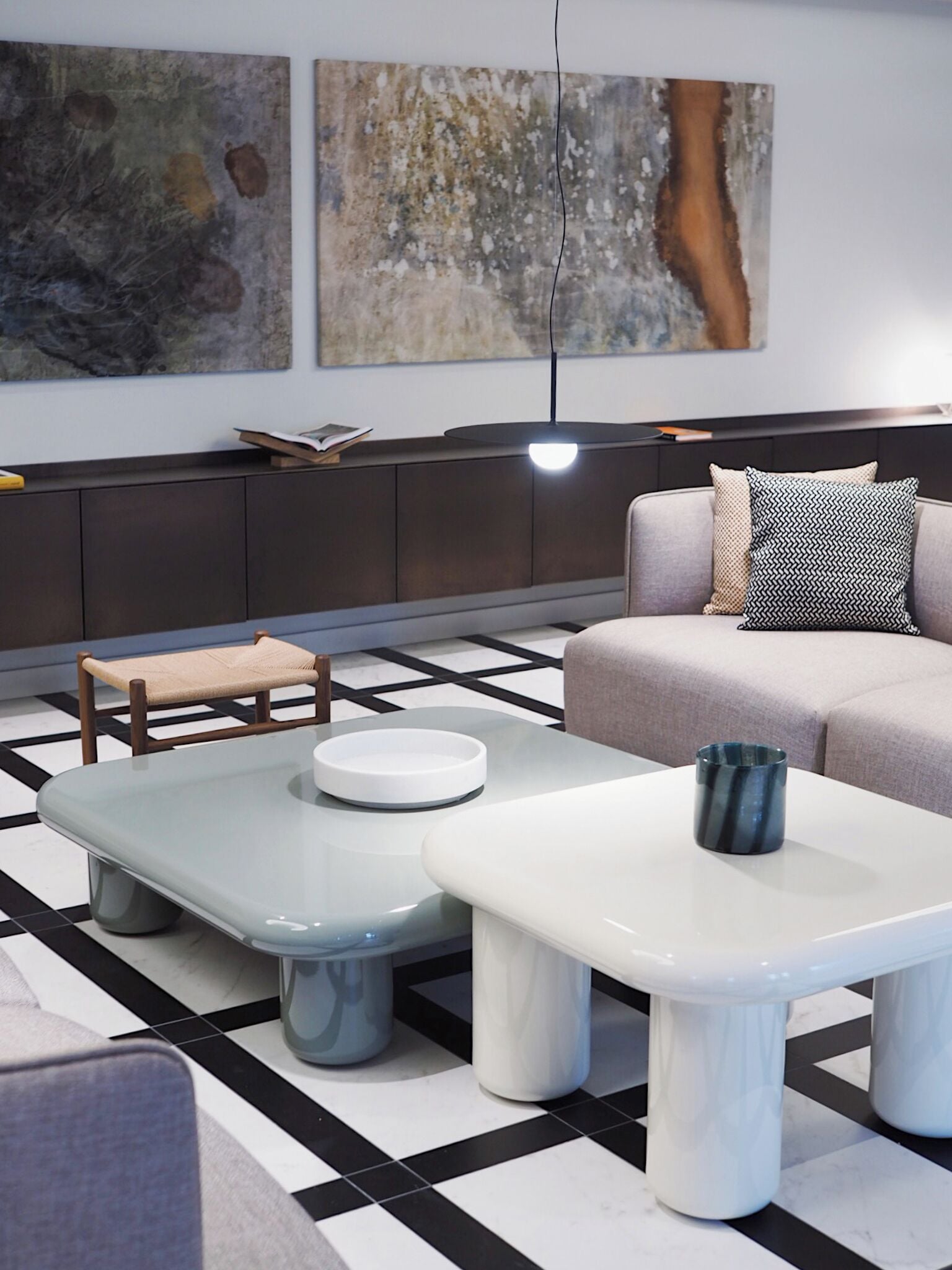A modern living room with a sofa, two coffee tables, a chair, and a bookshelf.