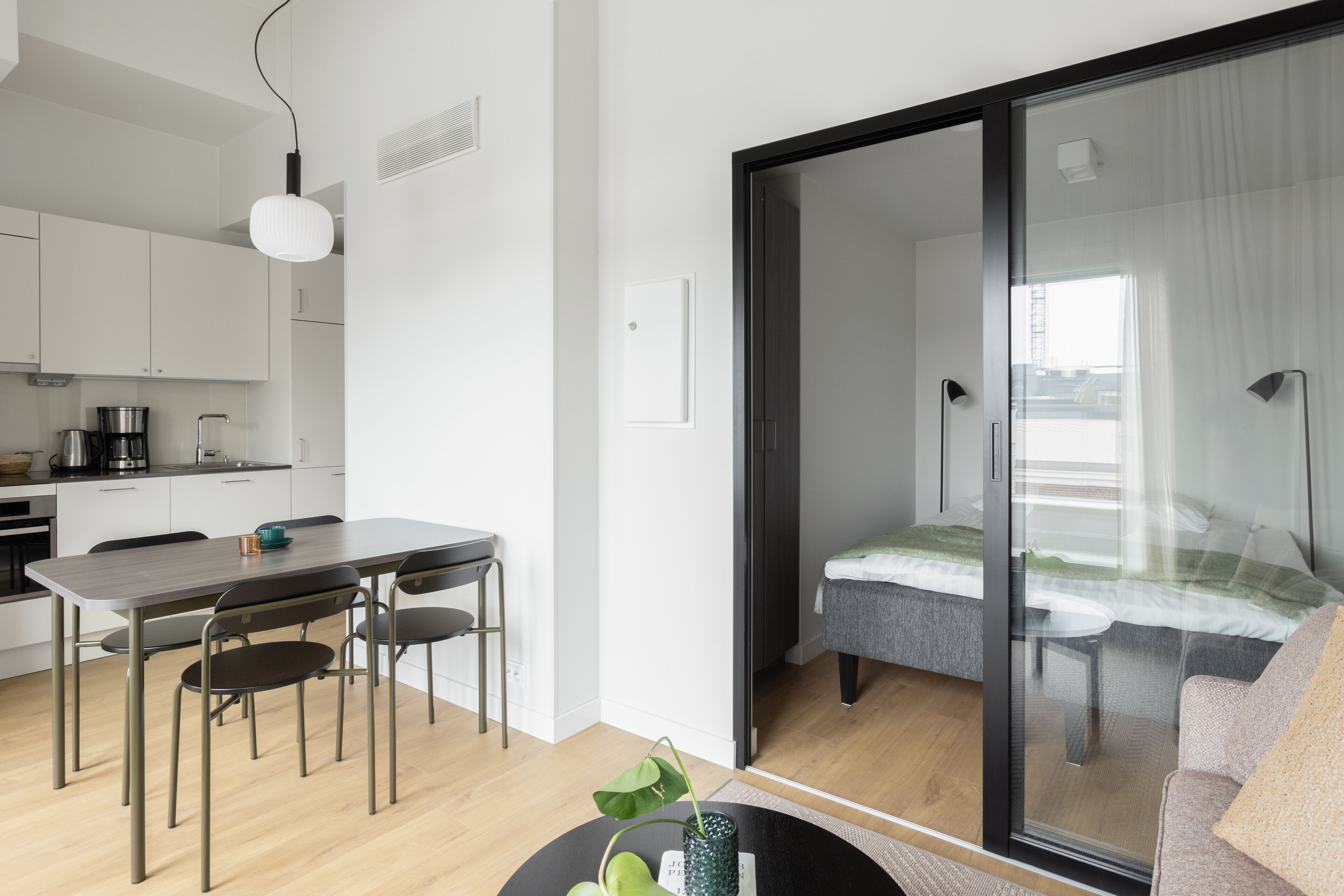 A modern kitchen with white cabinets, a dining table with chairs, and a coffee machine.