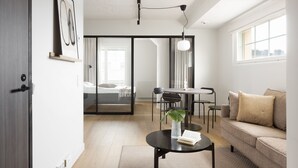 Ein modernes Wohnzimmer mit einer Couch, einem Couchtisch und einem Essbereich mit Stühlen und einem Tisch.