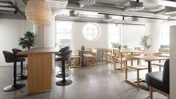 Un espace de bureau moderne doté d’un bar central, de tables rondes et de chaises.