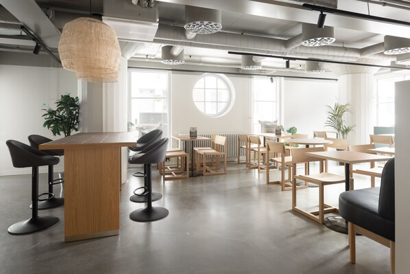 A modern office space with a central bar area, round tables, and chairs. - Noli Katajanokka II (Helsinki)