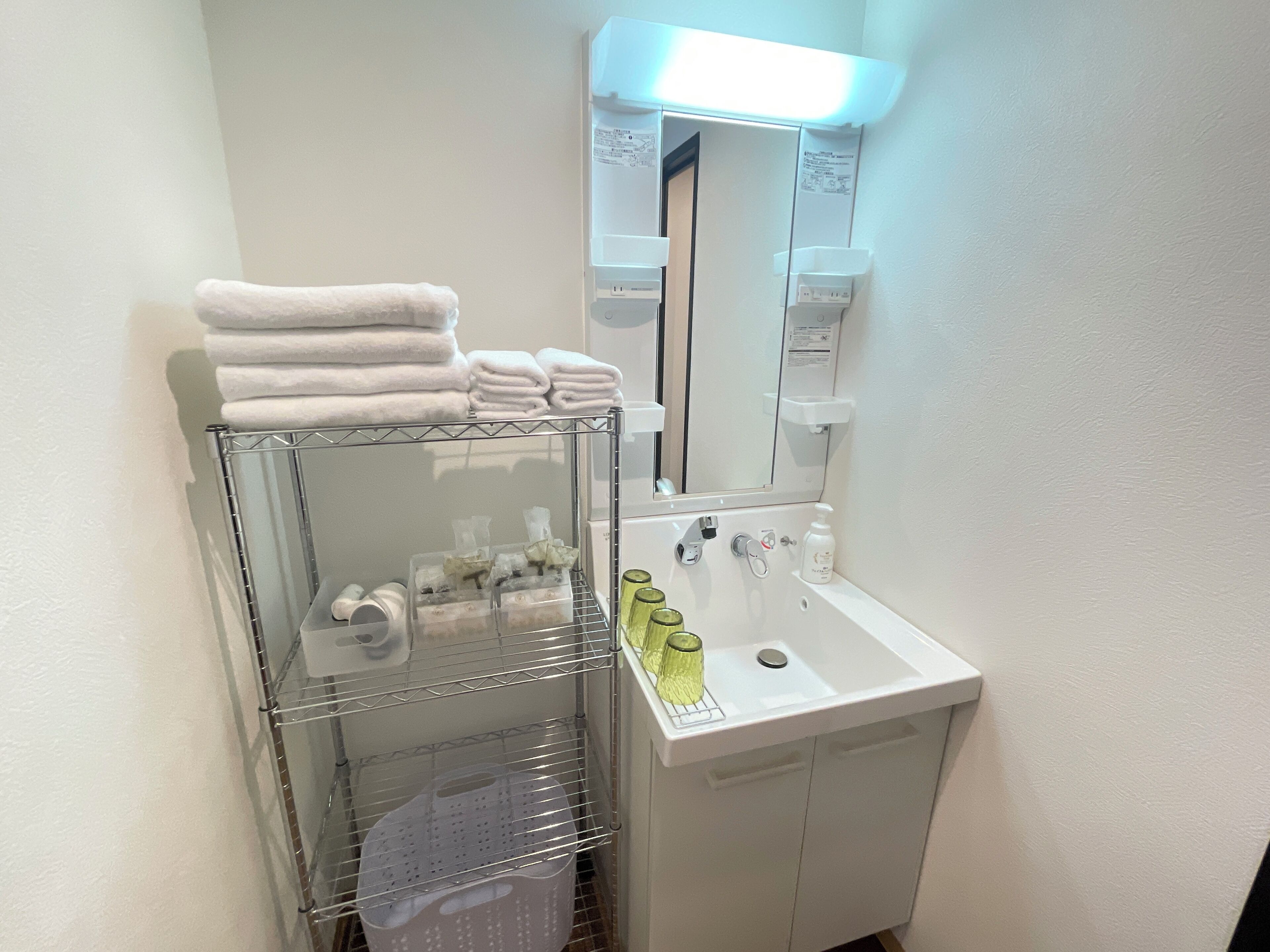 A bathroom with a sink, mirror, and shelves with towels and toiletries.