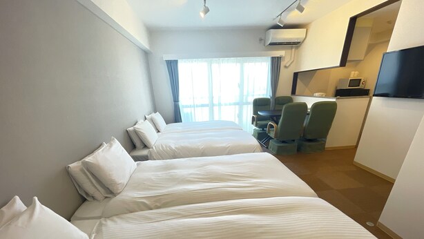 A hotel room with two beds, a desk with a chair, a TV, and a microwave. - BiBi Hotel Cosmos Shintoshin (Naha)