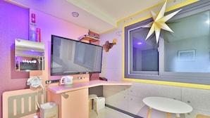 A modern hotel room with a large flat-screen TV, a desk with a computer, a small table, and a decorative star on the wall. - The Apple Hotel (Busan)