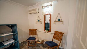 A room with two wooden chairs, a small table, a blue shelving unit, and a mirror with shelves above it. - Cunda Ada Kızı Otel (Ayvalik)