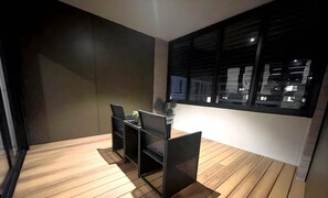 Un interior moderno con piso de madera, una mesa de comedor con sillas y un ventanal con vistas a la ciudad.