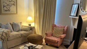 A cozy living room with a beige sofa, a pink armchair, a round coffee table, and a television on a wooden stand. - No. 4 on Bolton
 (Wagga Wagga)