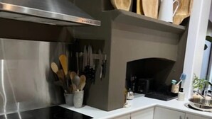 A modern kitchen with a stainless steel range hood, wooden cutting boards, and a variety of utensils on the wall. - No. 4 on Bolton
 (Wagga Wagga)
