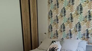 Een moderne slaapkamer met een groot bed, een houten plafondlamp en een muur met een bladmotief.