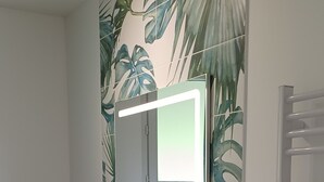 Un baño con tocador blanco, espejo y retrete.