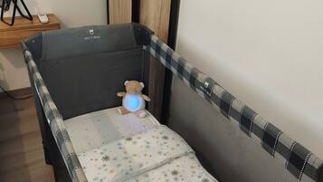 Ein Babybett mit einem gemusterten Matratze, einem Teddybären und einer Babywiege mit blauem Licht.