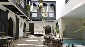 A courtyard with a pool, outdoor seating, and a dining area. - Riad Spa Le Secret de Zoraida (Marrakech)