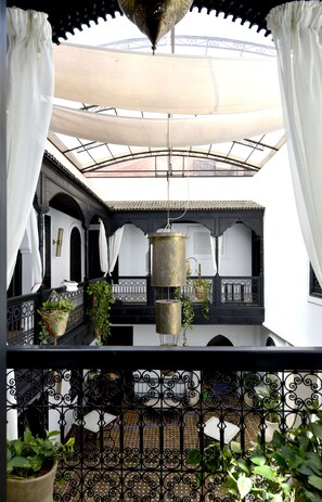 A courtyard with a covered area, potted plants, and a hanging lamp. - Riad Spa Le Secret de Zoraida (Marrakech)
