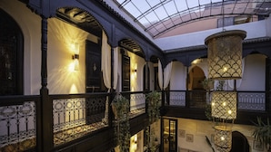 A multi-level interior with ornate iron railings, hanging lanterns, and a cozy seating area with cushions. - Riad Spa Le Secret de Zoraida (Marrakech)