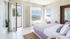 Een slaapkamer met een groot bed, uitzicht op zee en een schuifdeur naar het balkon.