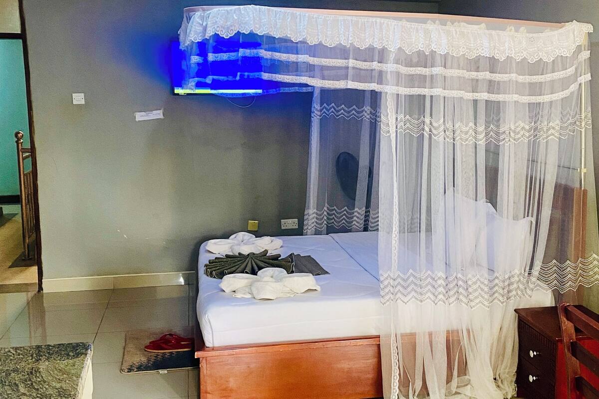 A room with a bed, a wooden nightstand, and a mirror.