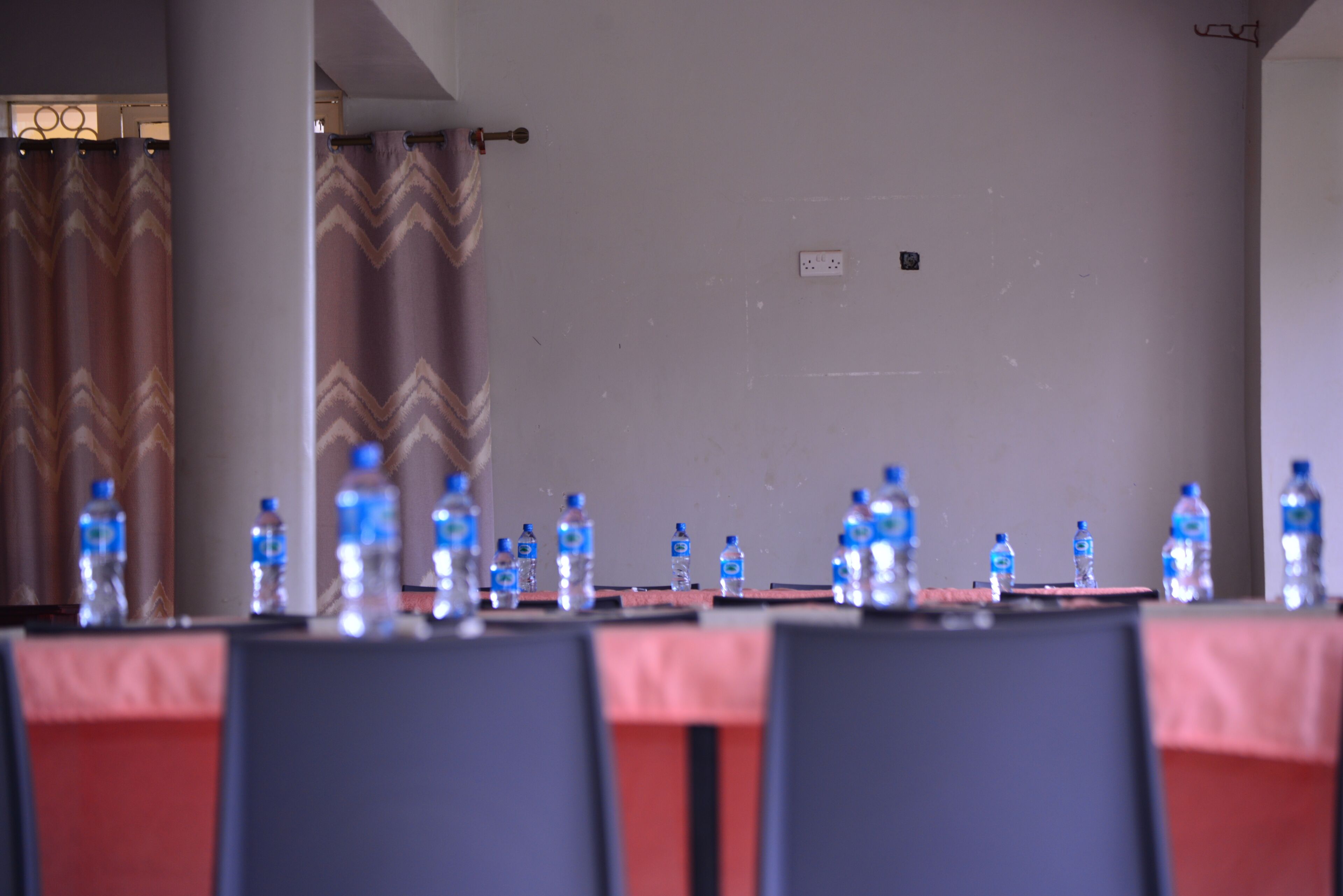 Une salle de conférence avec une longue table, des chaises et des bouteilles d’eau.